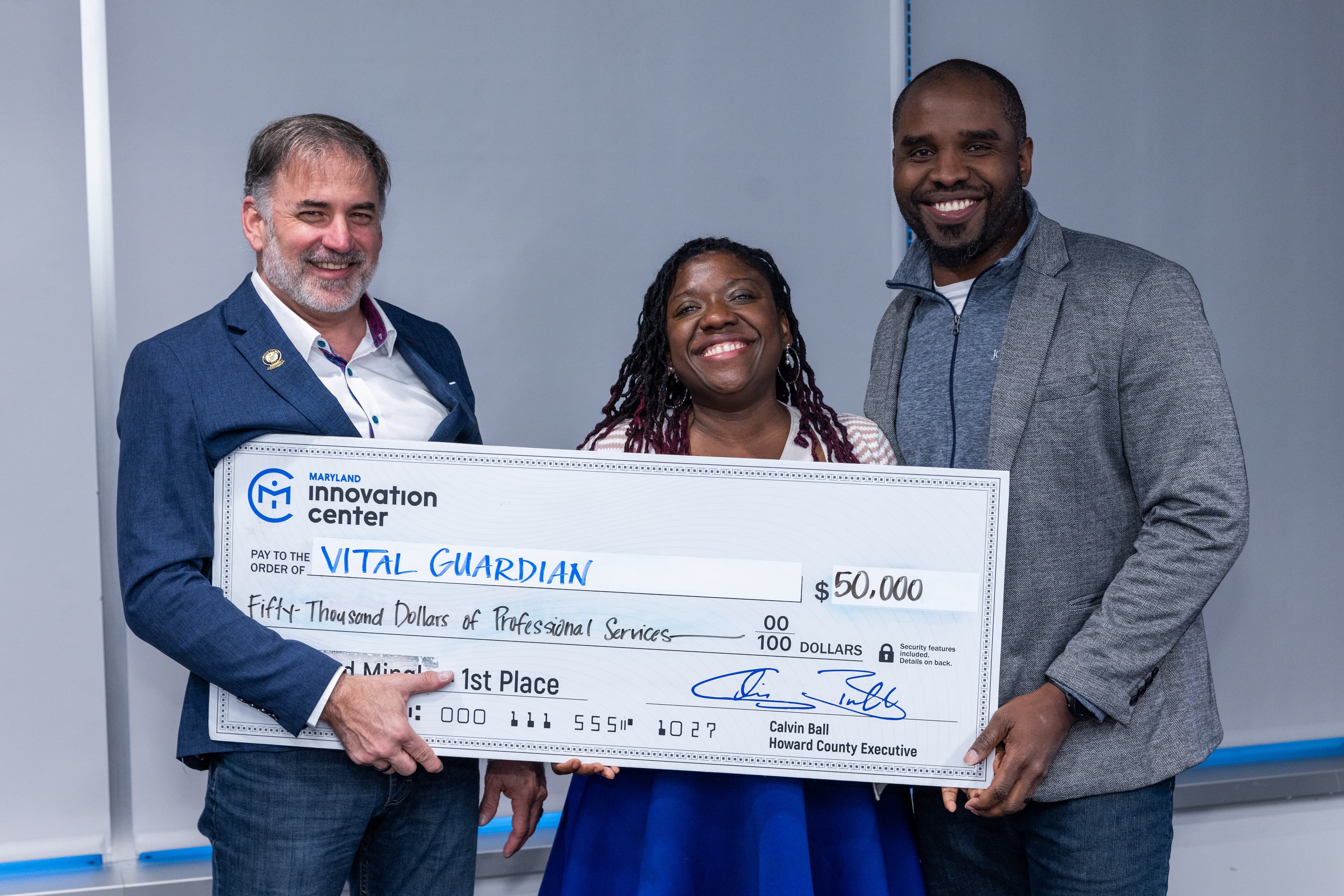 VitalGuardian team accepting the $50,000 first place check from Howard County Executive Calvin Ball at Maryland Innovation Center Pitch and Mingle, April 21, 2026